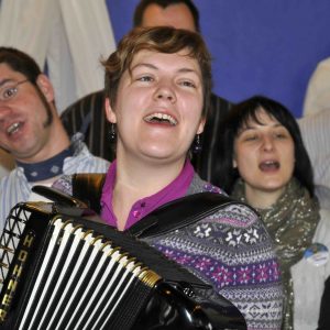 Fröhlich singende Menschen mit Akkordeon begleitet