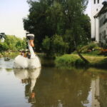 Ein Boot in Form eines Schwans fährt über den Dorfweiher