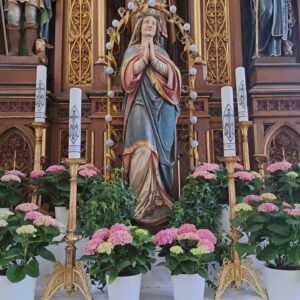 Marienstatue umgeben mit Kerzen und Blumen
