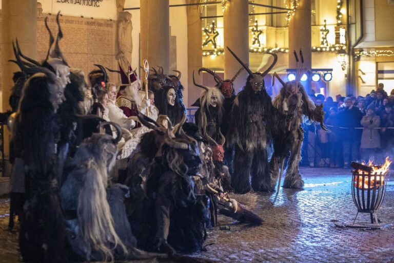 Gruselig verkleidete stehen Nachts auf einem Platz in einem Halbkreis um ein Feuer.