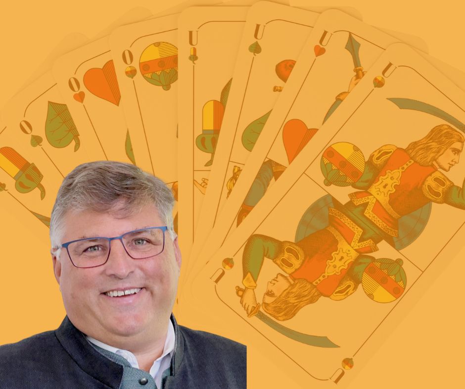 Landrat Stefan Löwl im Porträt. Hinter ihm aufgefächerte Schafkopf-Karten